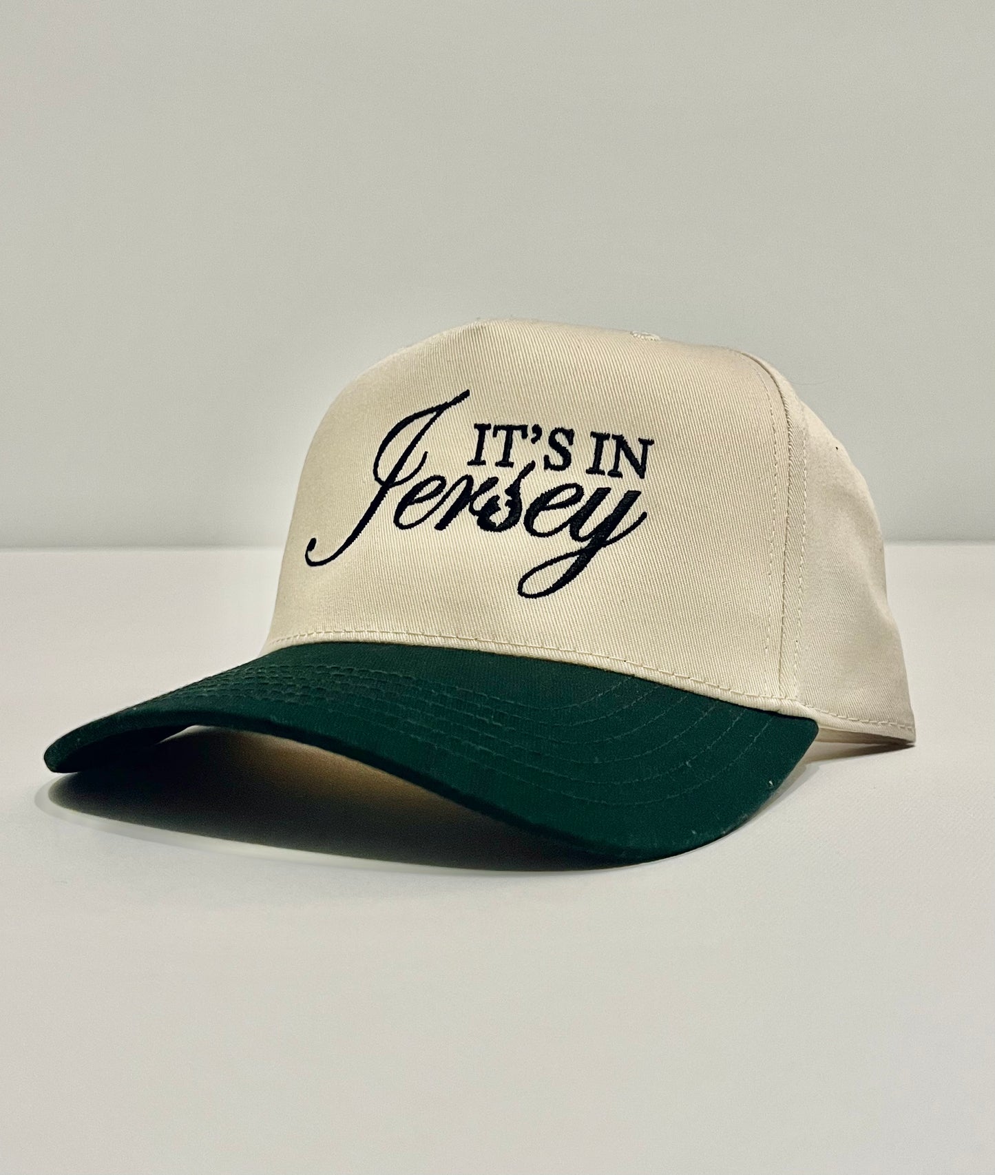 Natural snapback with dk. green bill and 'It's in Jersey' embroidery