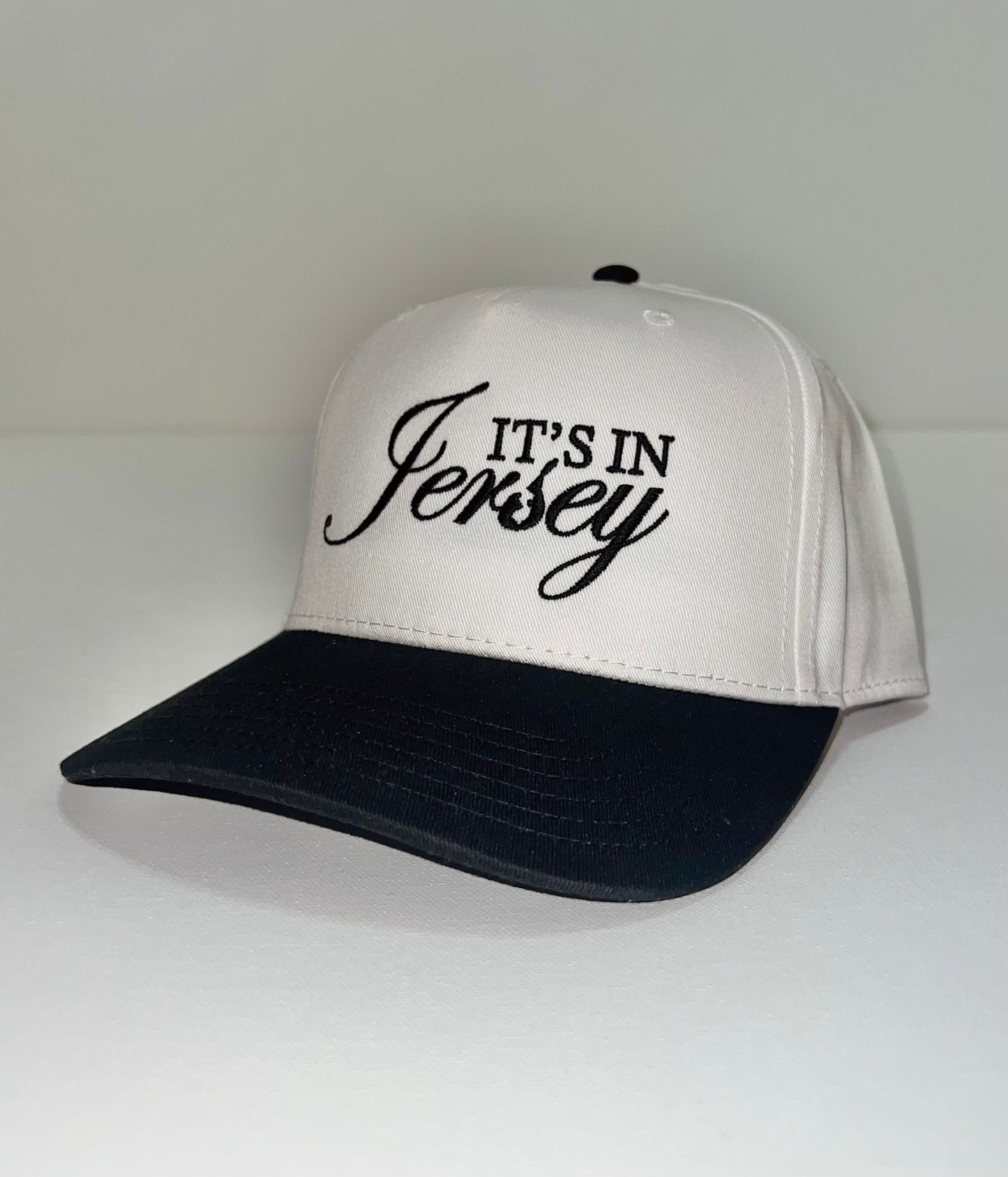 White snapback with black bill and 'It's in Jersey' embroidery