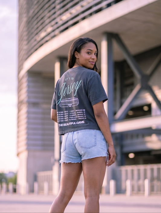 Woman wearing a graphic t-shirt and denim shorts standing in front of MetLife Stadium
